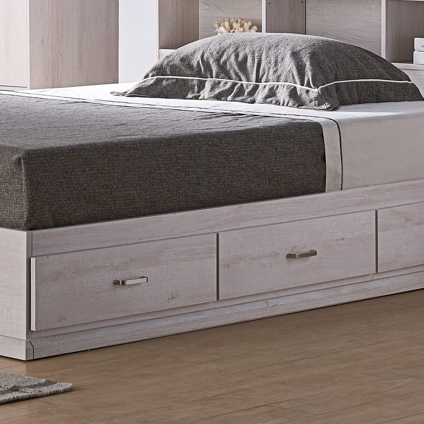 Left angled bird's eye close-up view of a contemporary white oak three-drawer platform storage bed in a bedroom with accessories
