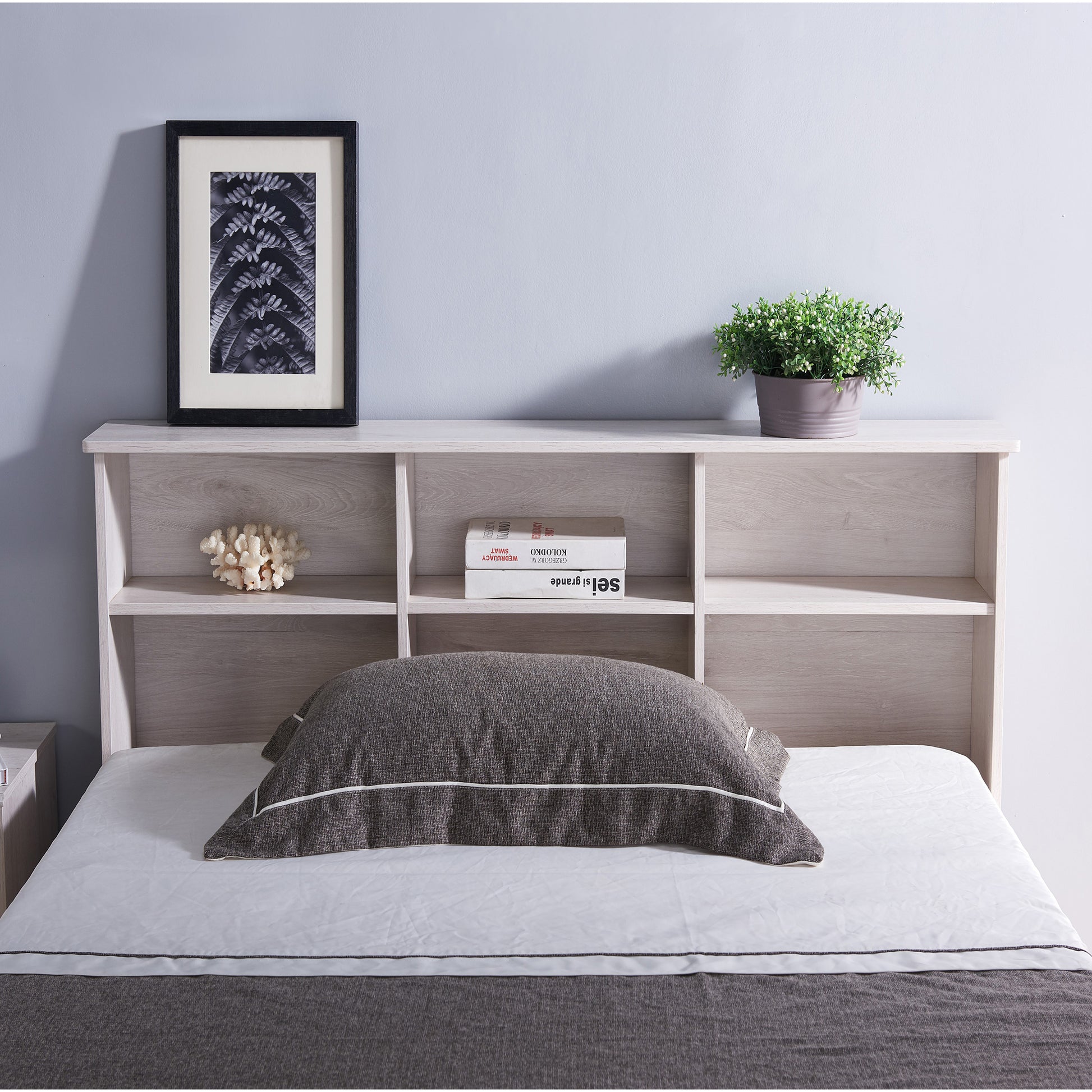 Front-facing transitional white oak six-shelf bookcase headboard shown with a bed in a bedroom with accessories