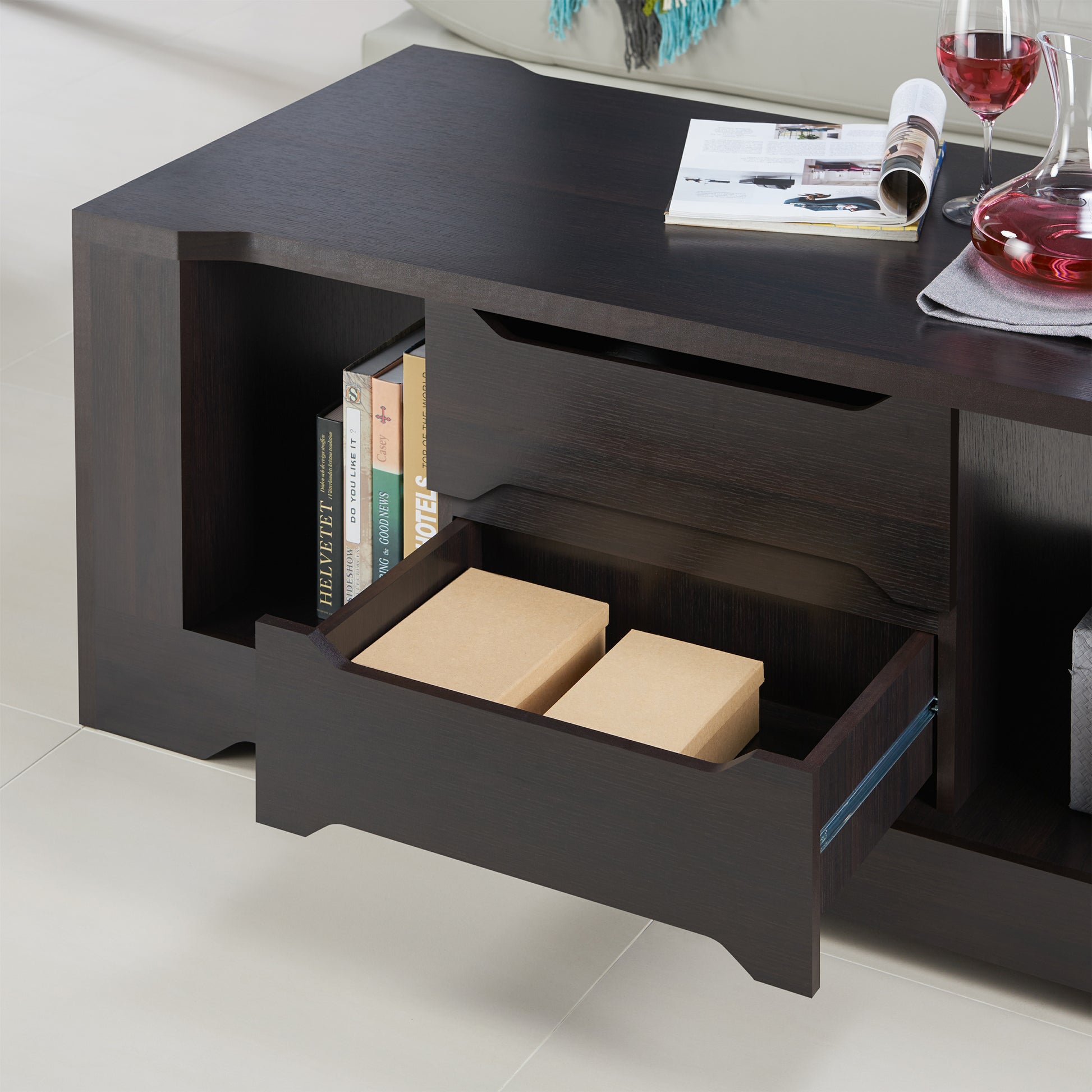 Left angled close up of a transitional espresso two-drawer storage coffee table with bottom drawer open in a living room with accessories