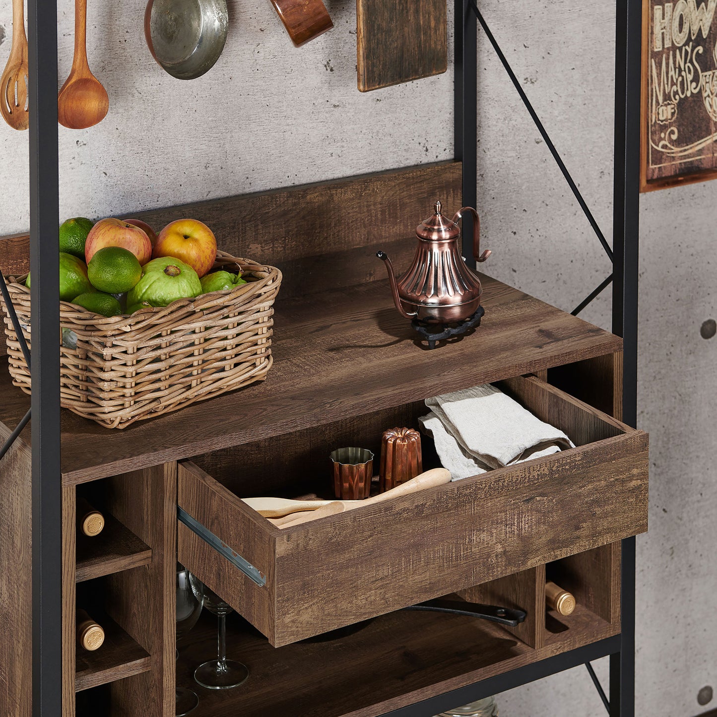 Right angled close-up of a industrial reclaimed oak and black multi-shelf baker's rack with hooks and drawer open in a living area with accessories