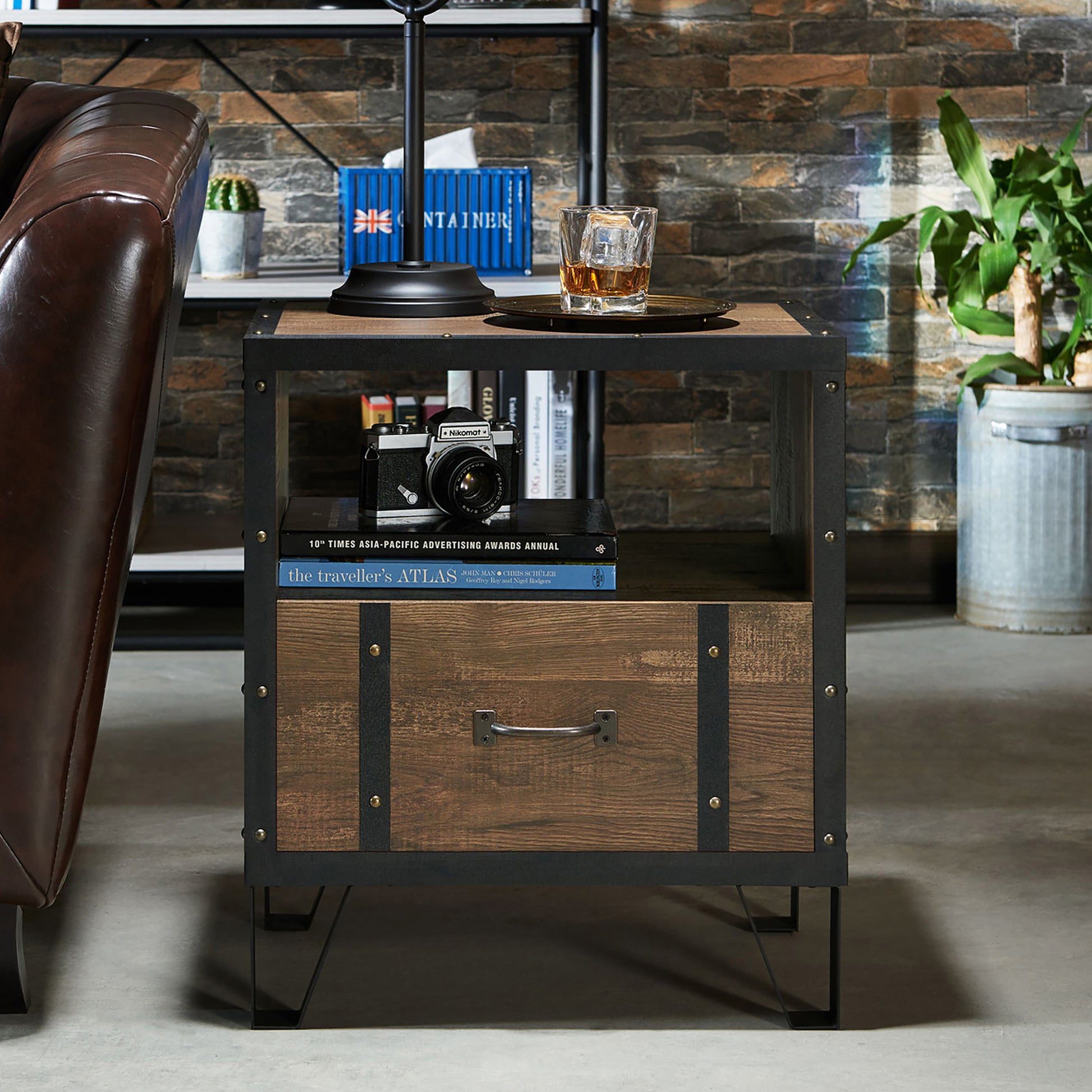 Front-facing industrial reclaimed oak and black one shelf one drawer end table in a living room with accessories