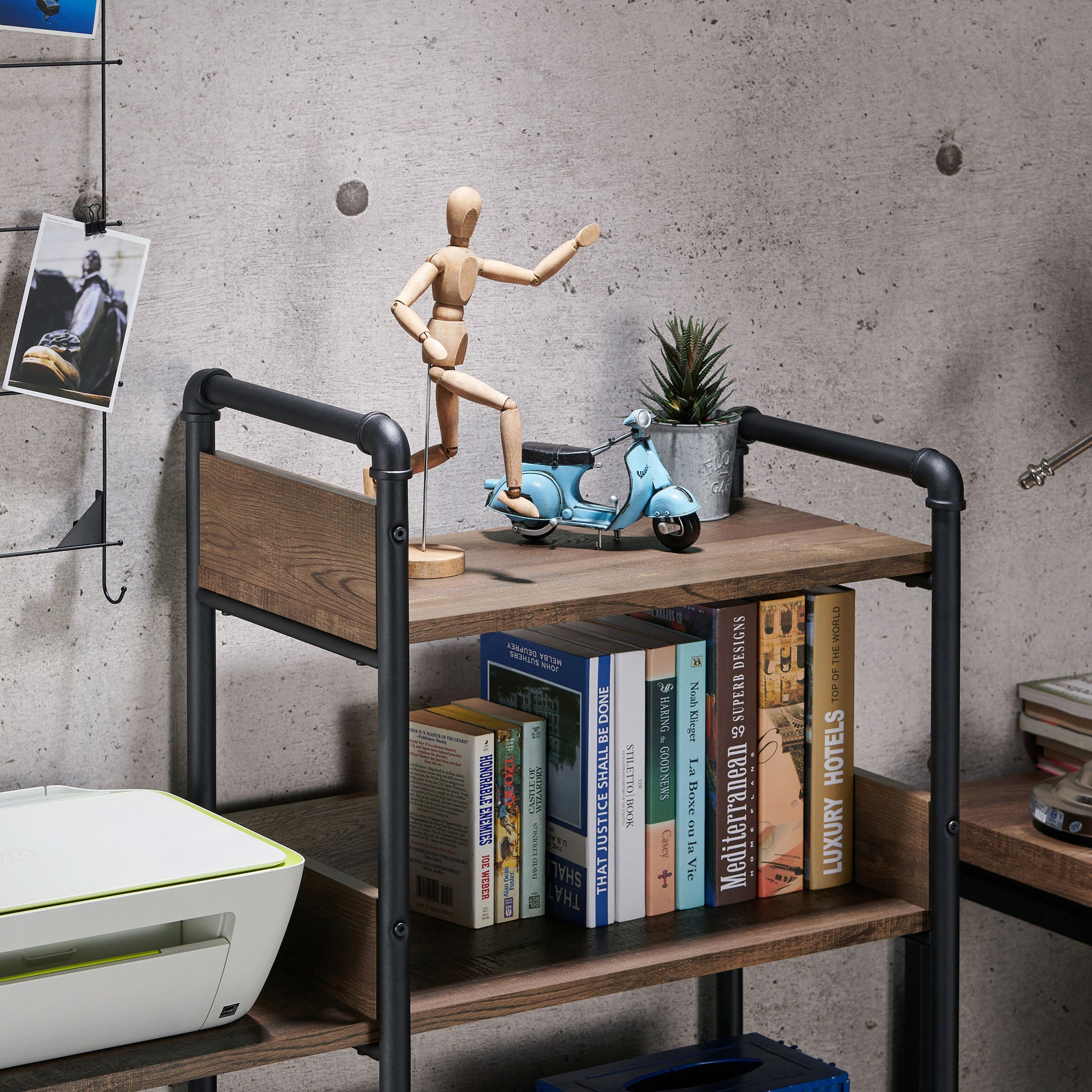 Left angled close-up view of an industrial reclaimed oak and black water pipe six-shelf open bookcase in a home office with accessories