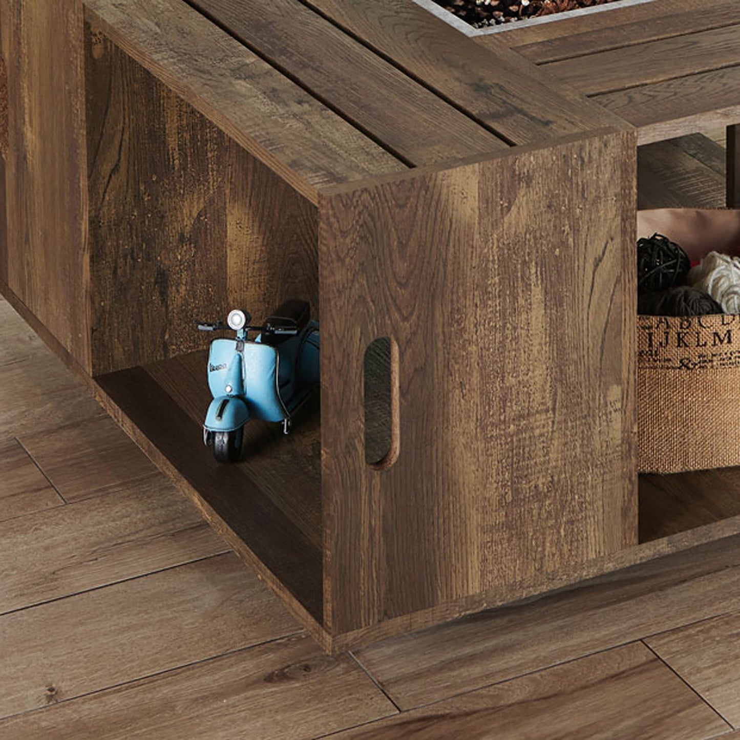 Angled close-up view of a rustic reclaimed oak crate-style mobile storage coffee table on a wood floor with accessories