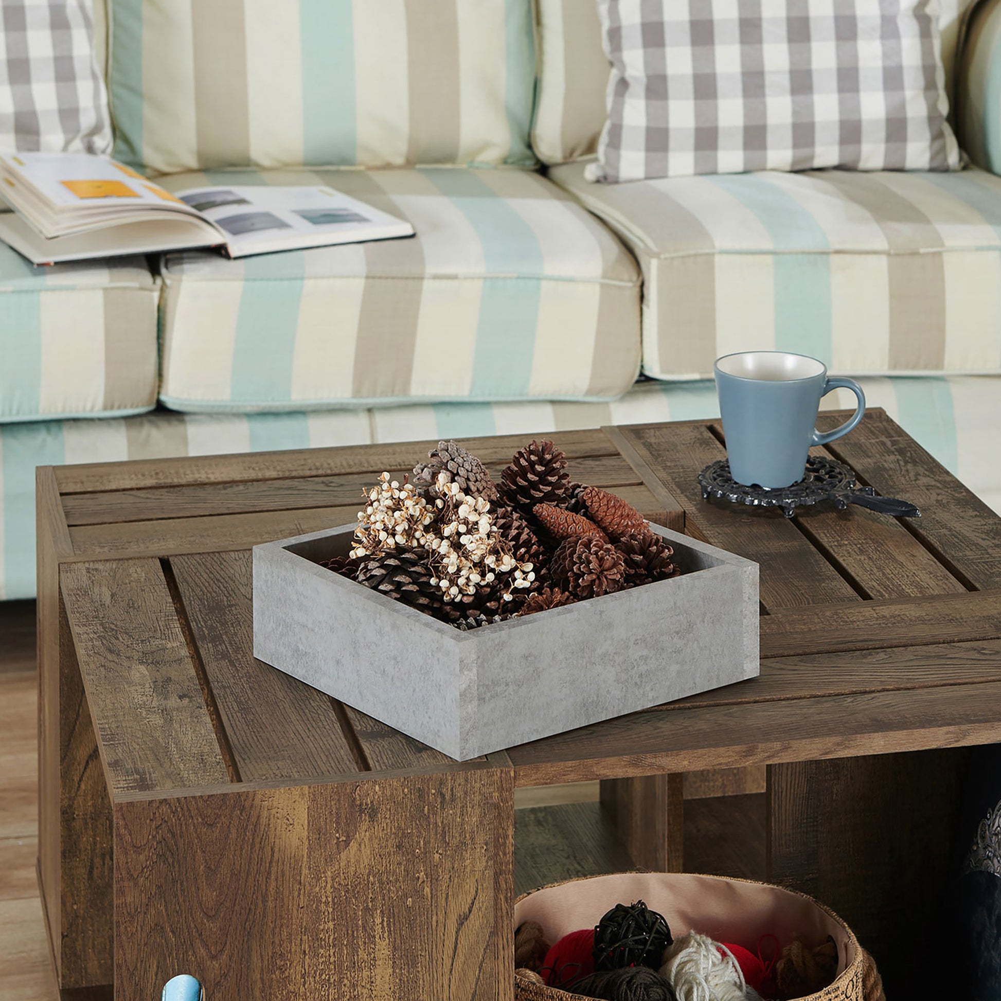 Left angled close-up view of a rustic reclaimed oak crate-style mobile storage coffee table with gray insert tray removed in a living room with accessories