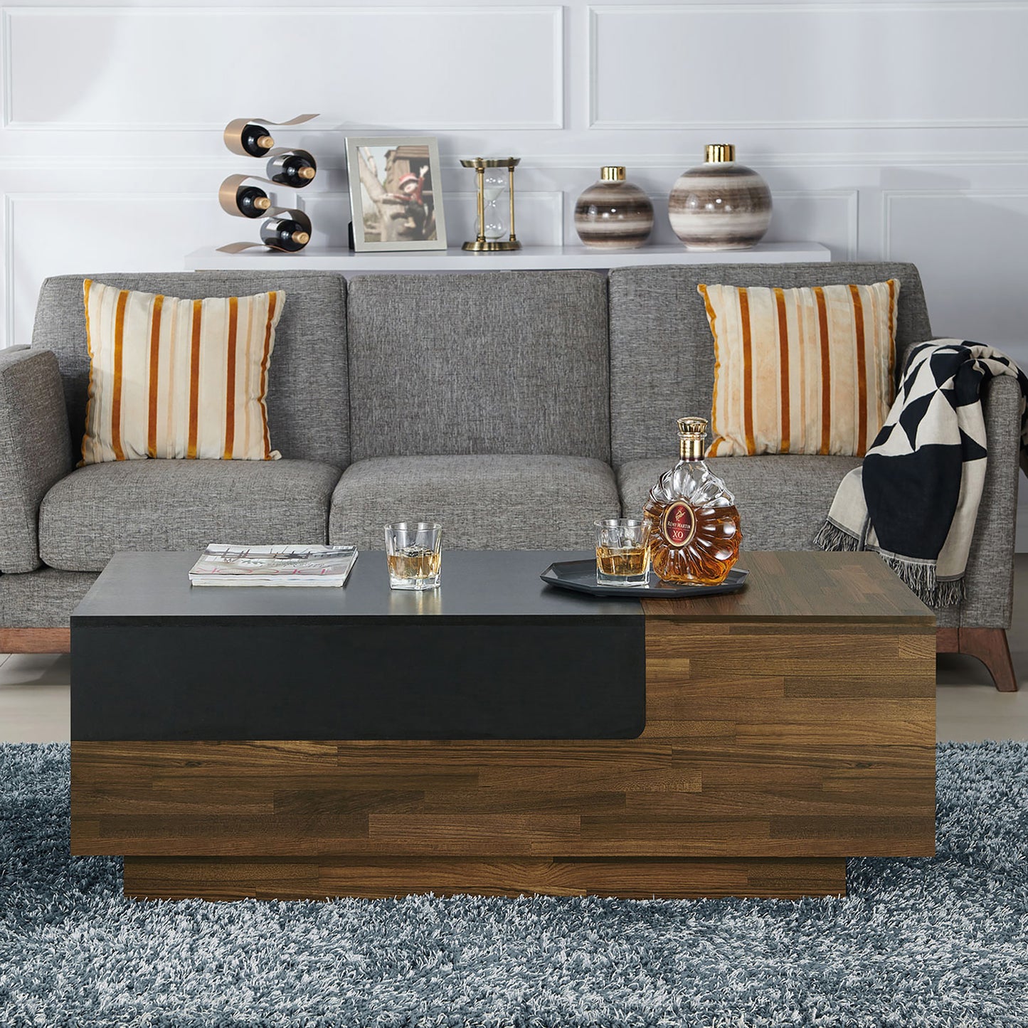 Front-facing contemporary light hickory and black sliding top one-drawer coffee table in a living room with accessories
