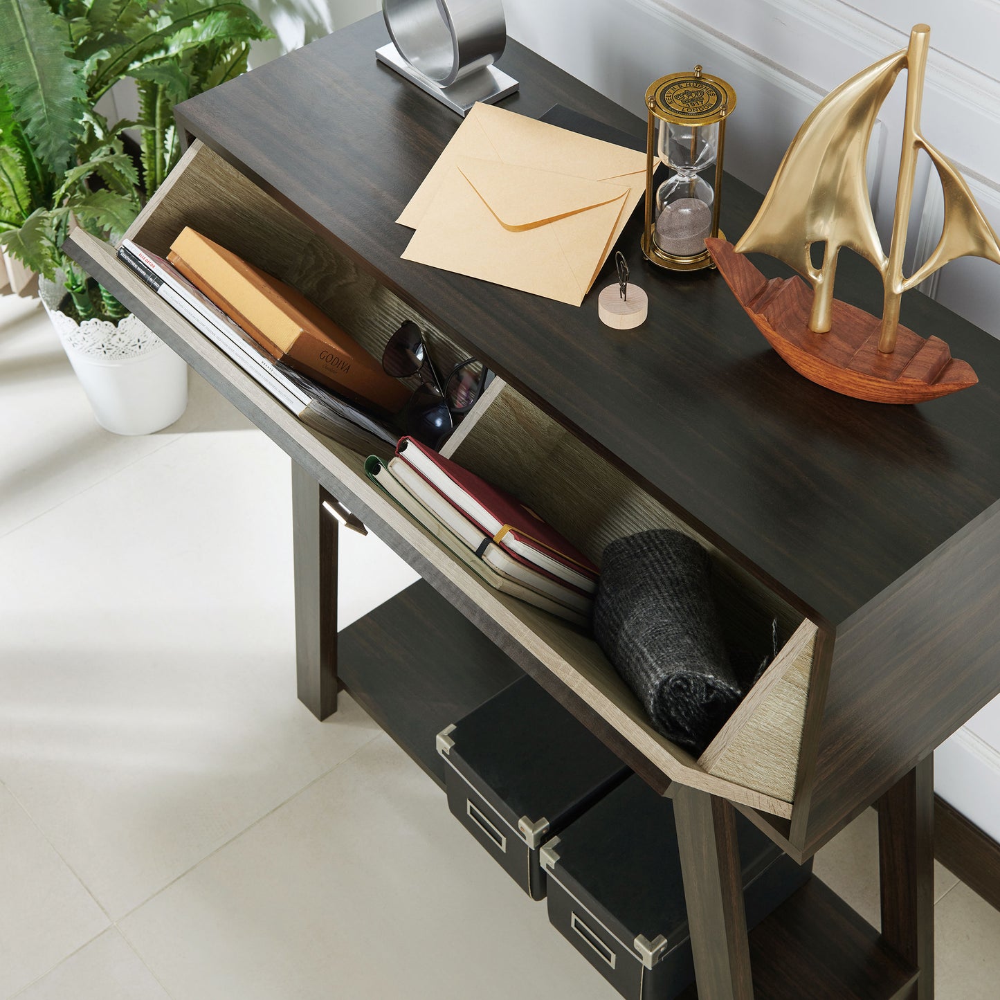 Left angled bird's eye view of a modern wenge and light wood one-drawer console table with a shelf with drawer open in a living room with accessories