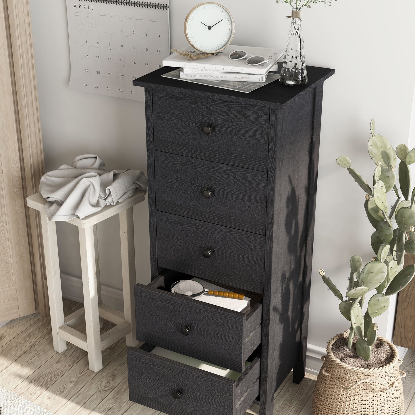 Left angled transitional black slim five-drawer chest with two drawers open in a living area with accessories