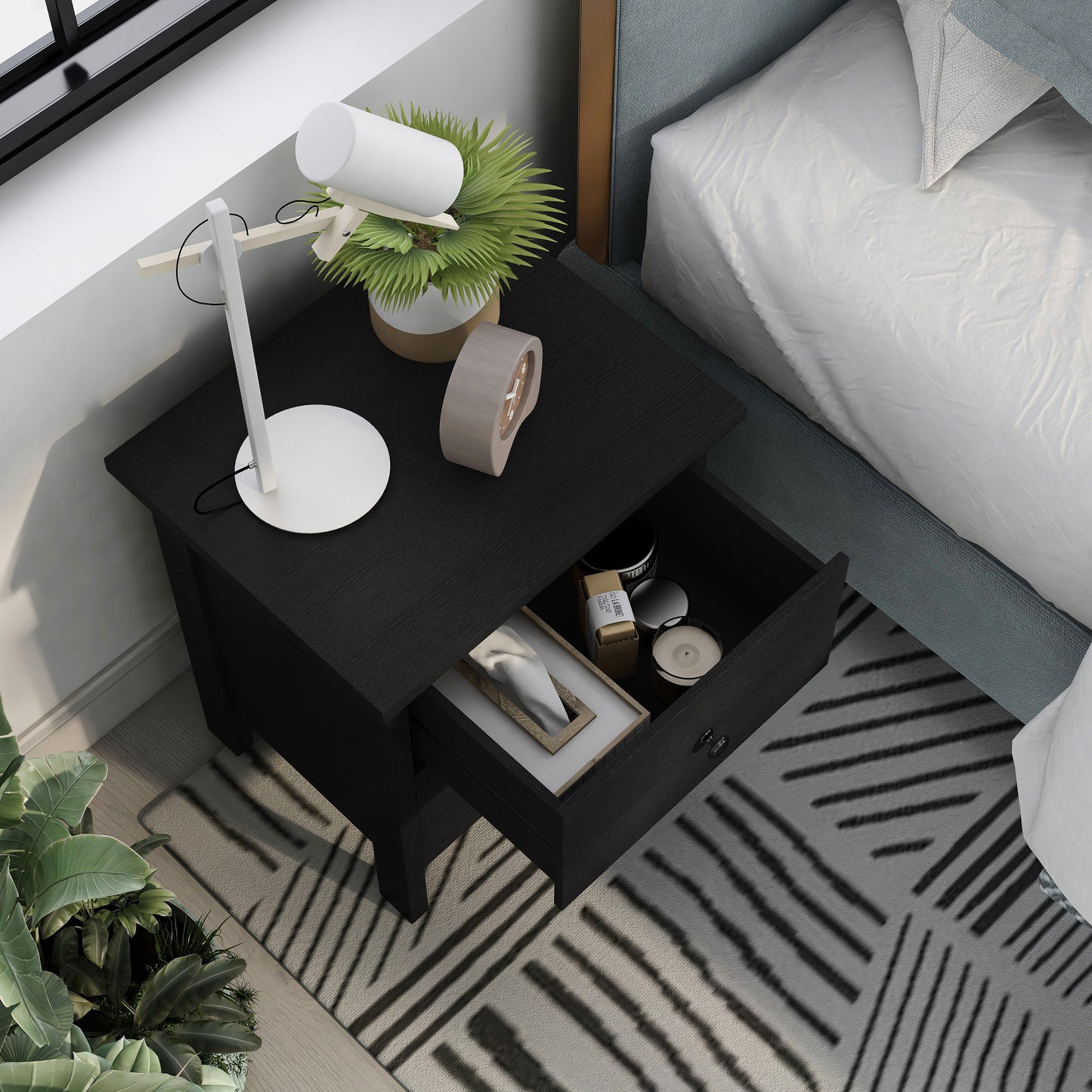Right angled bird's eye view of a transitional black two-drawer nightstand with top drawer open in a bedroom with accessories
