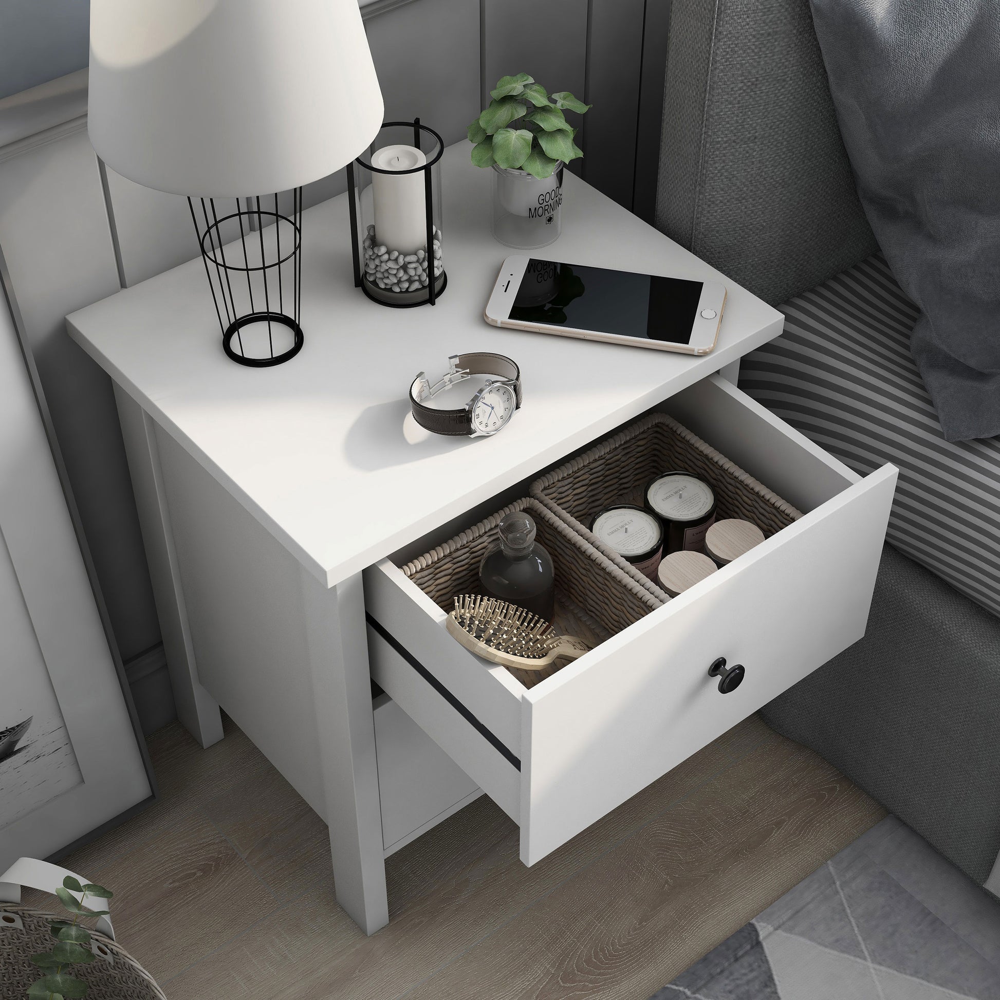 Right angled bird's eye view of a transitional white two-drawer nightstand with top drawer open in a bedroom with accessories