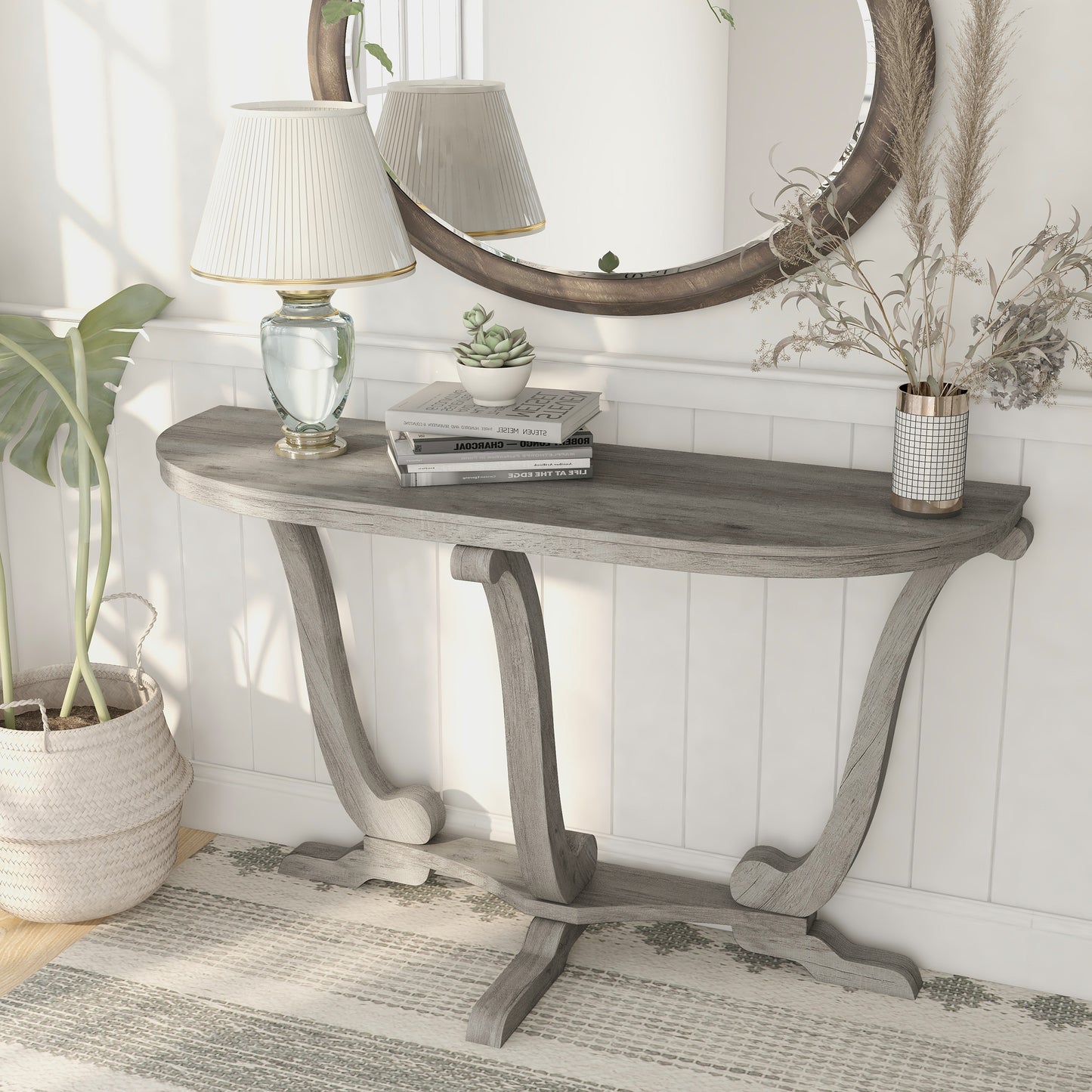 Left angled farmhouse vintage gray oak curved pedestal console table in a living area with accessories
