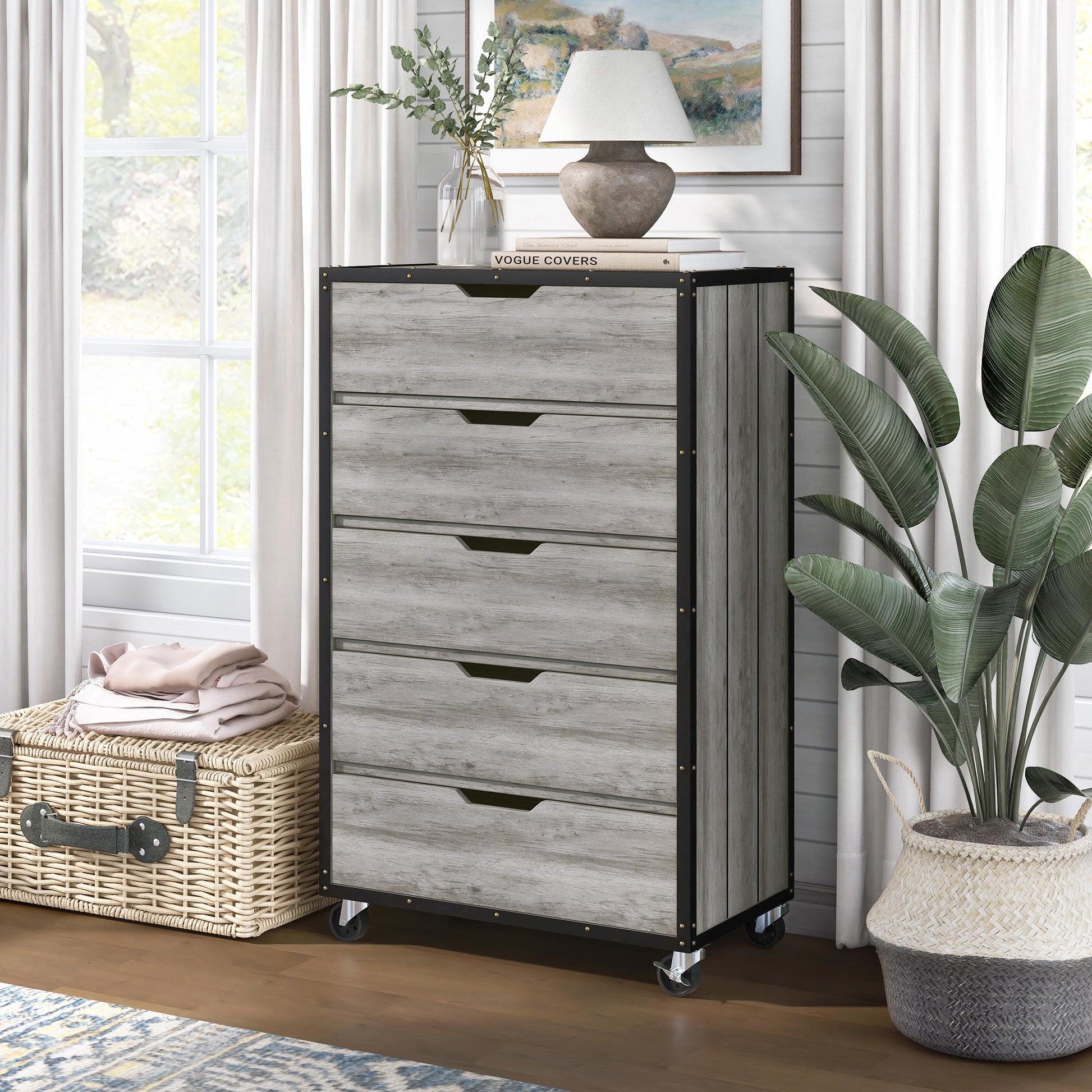 Left angled industrial vintage gray oak and black five-drawer mobile chest dresser in a living area with accessories