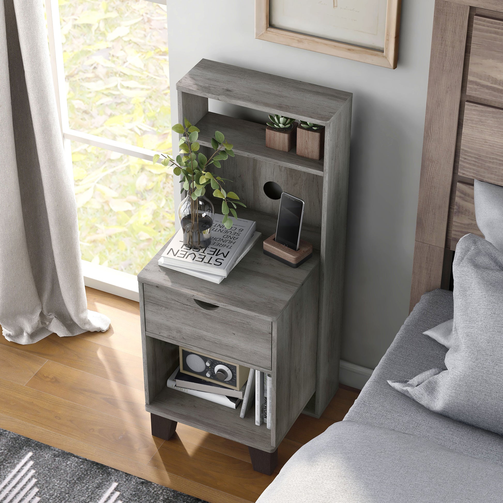 Left angled bird's eye view of a transitional vintage gray oak three-shelf nightstand with one drawer in a bedroom with accessories