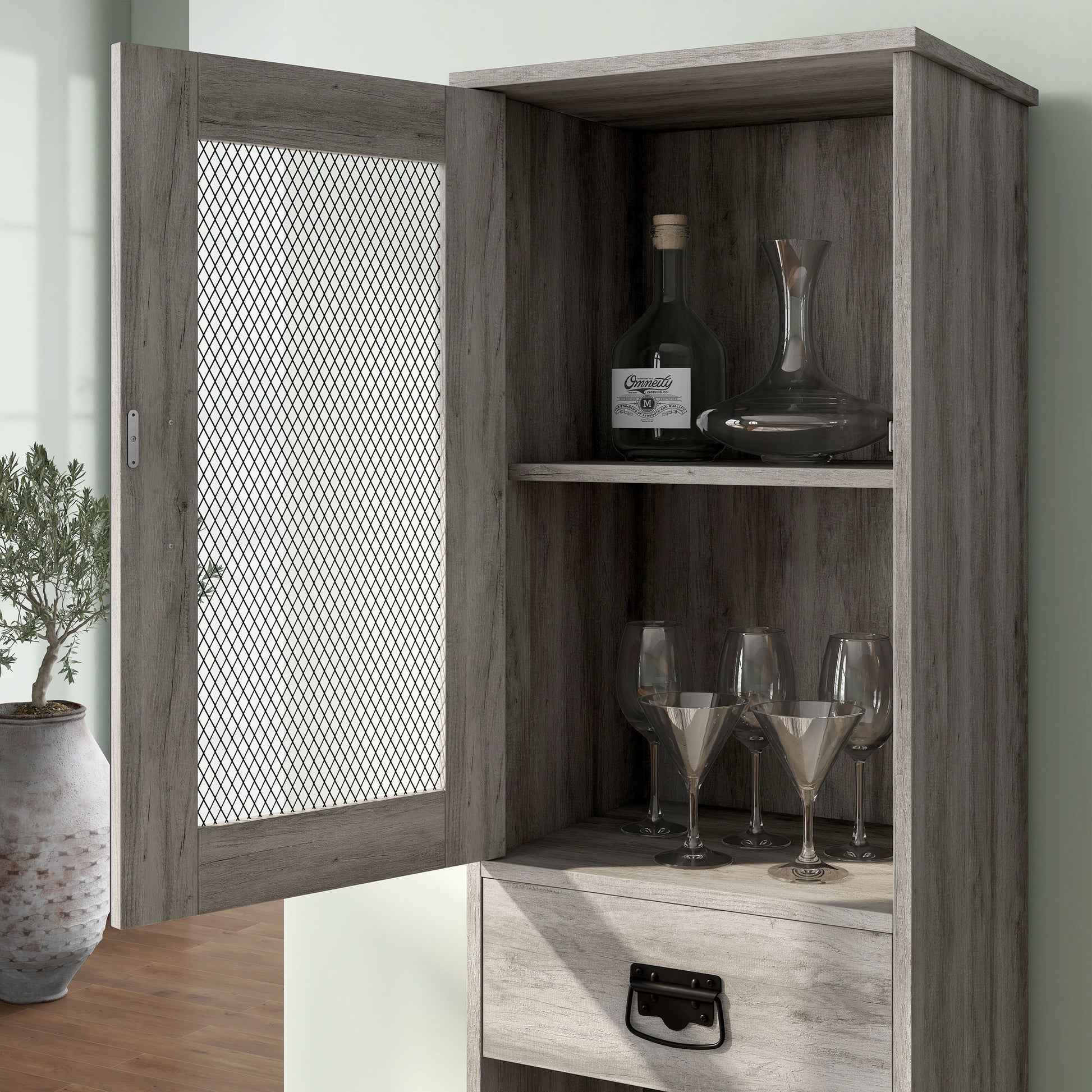 Left angled close-up shelf/mesh door view of an industrial vintage gray oak three-shelf tower cabinet with wine storage in a living area with accessories