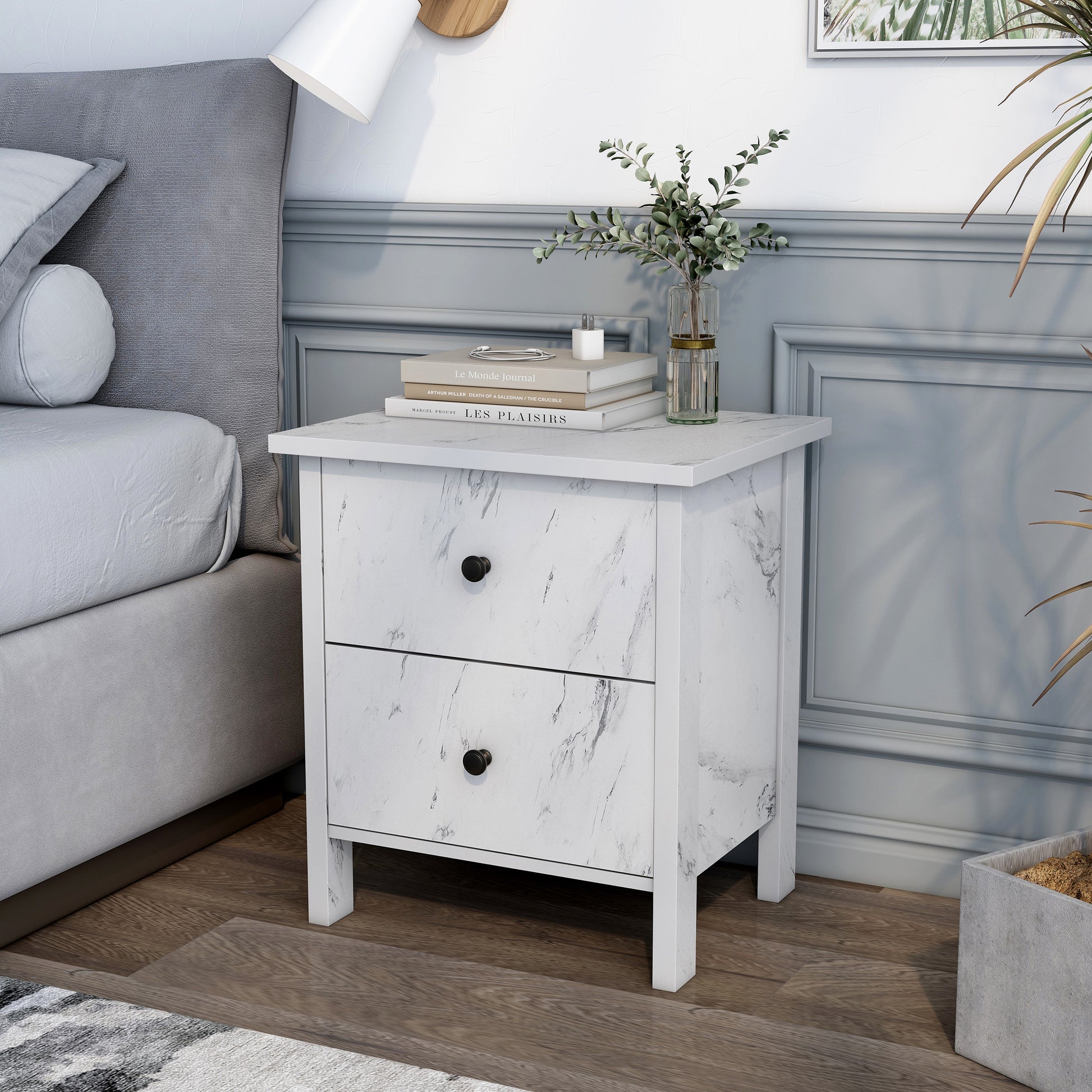 Left angled transitional white faux marble two-drawer nightstand in a bedroom with accessories