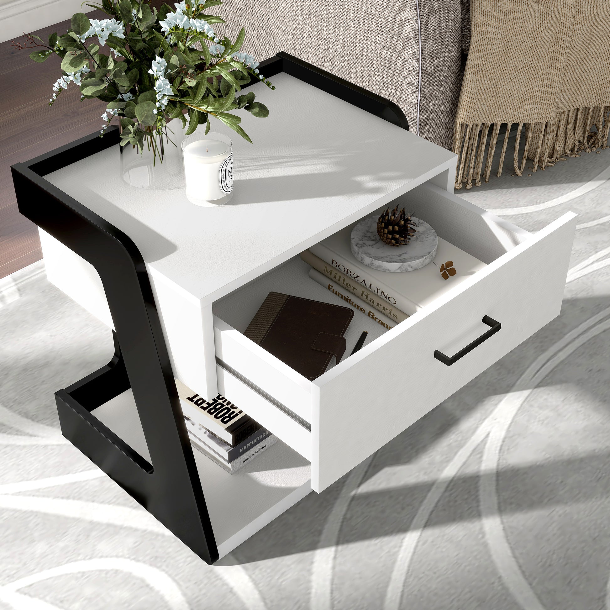Right angled bird's eye view of a contemporary white and black one-drawer side table with a shelf and drawer open in a living room with accessories